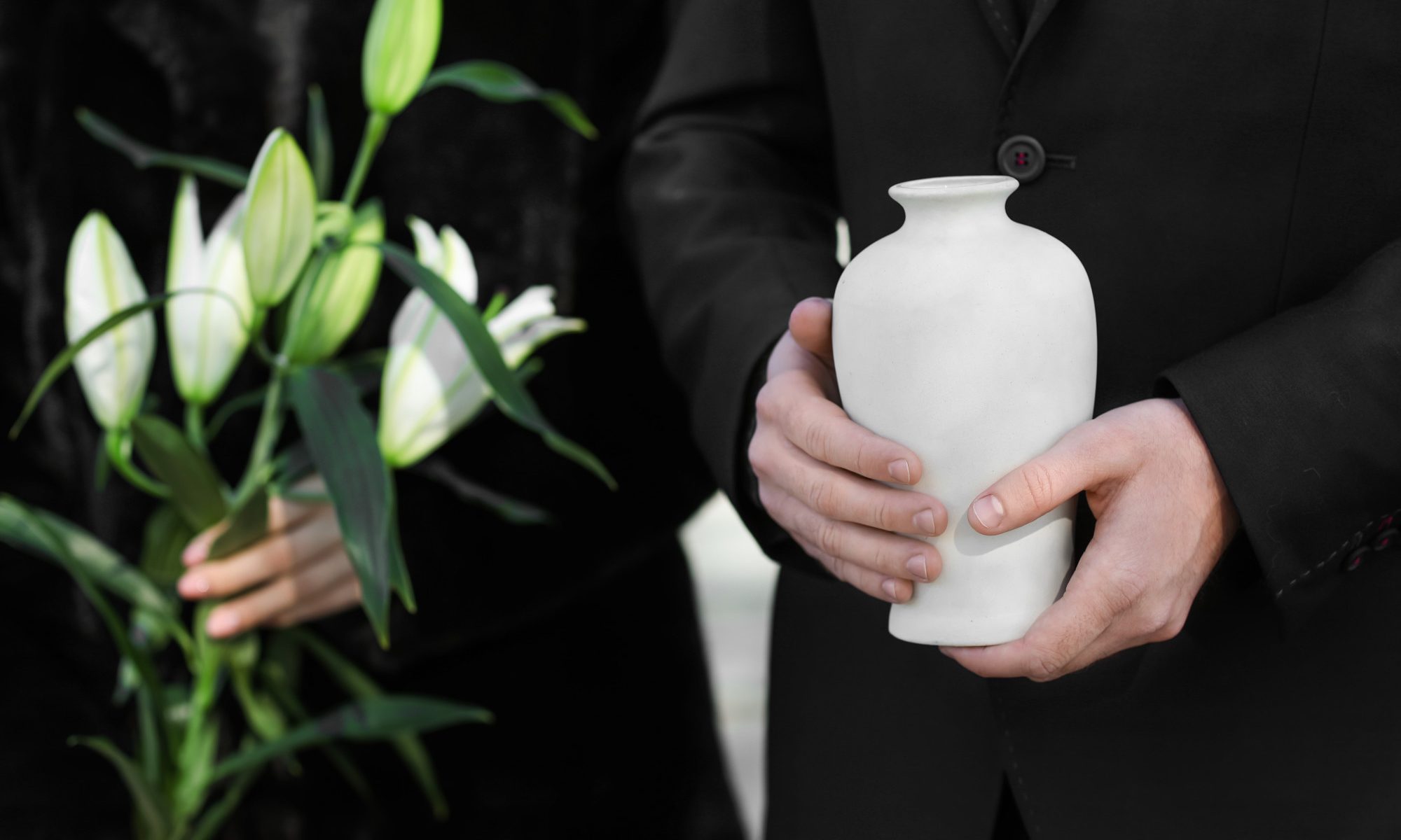 Couple with mortuary urn and flowers at cremation or burial